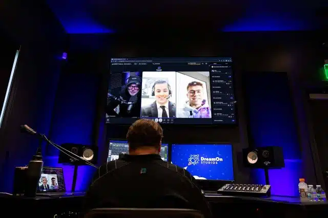 Man sitting in front of a multi-monitor video display.