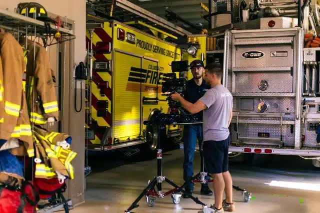Two men standing with video equipment at a fire department preparing to shoot a commercial campaign.