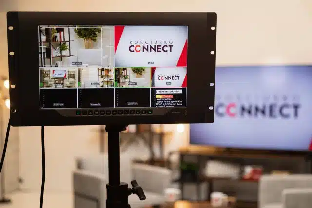 Large video monitor displaying the Kosciusko Connect logo and information during a live streaming session.